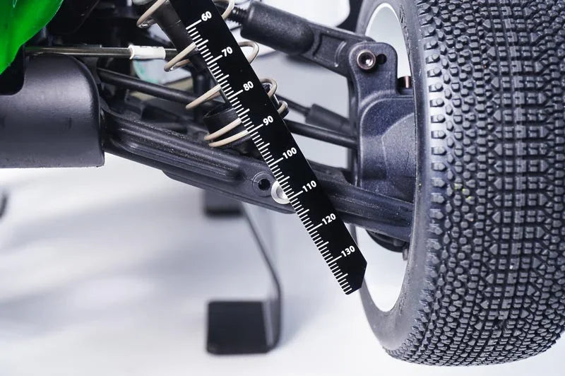 Close-up of RC car suspension with ride height gauge tool measuring shock absorber