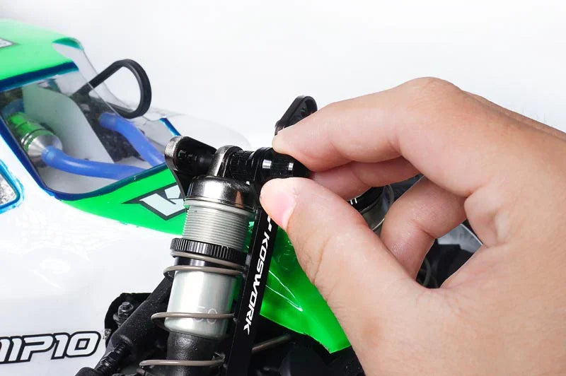 Hand adjusting RC car shock absorber with Koswork tool on green and white remote control vehicle