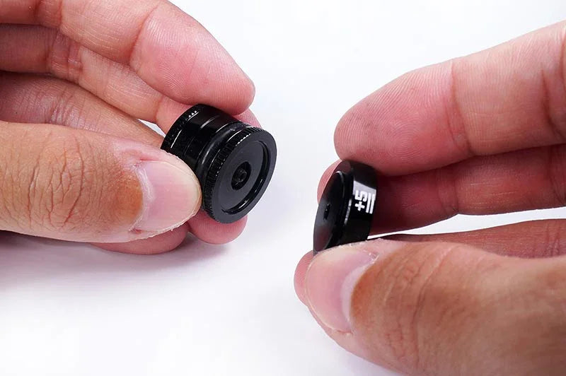 Hands holding black RC car parts with adjustment markings on a white background