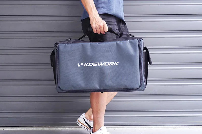 Person carrying a large Koswork RC pit bag with handle in front of a gray garage door.