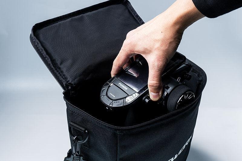 Hand placing RC car remote controller into a black padded carrying bag for RC accessories