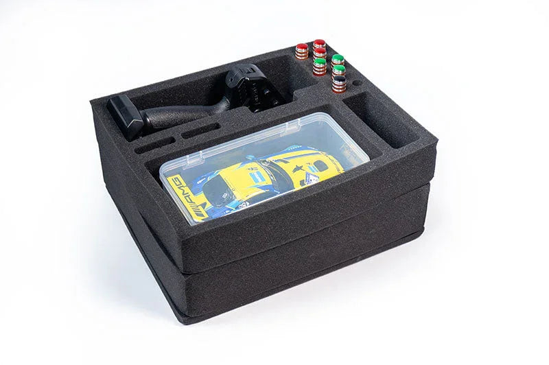 Foam RC car storage box with compartments holding a remote, mini car, and accessories.
