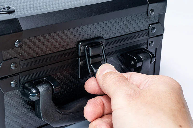 Hand unlatching a black RC tool storage case with carbon fiber texture and sturdy handle