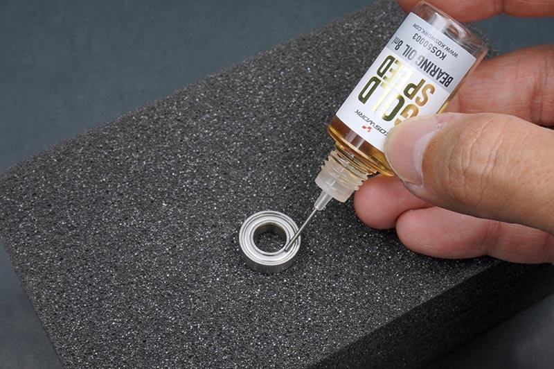 Koswork KOS50003-3 RC bearing oil being applied to a metal bearing on black foam