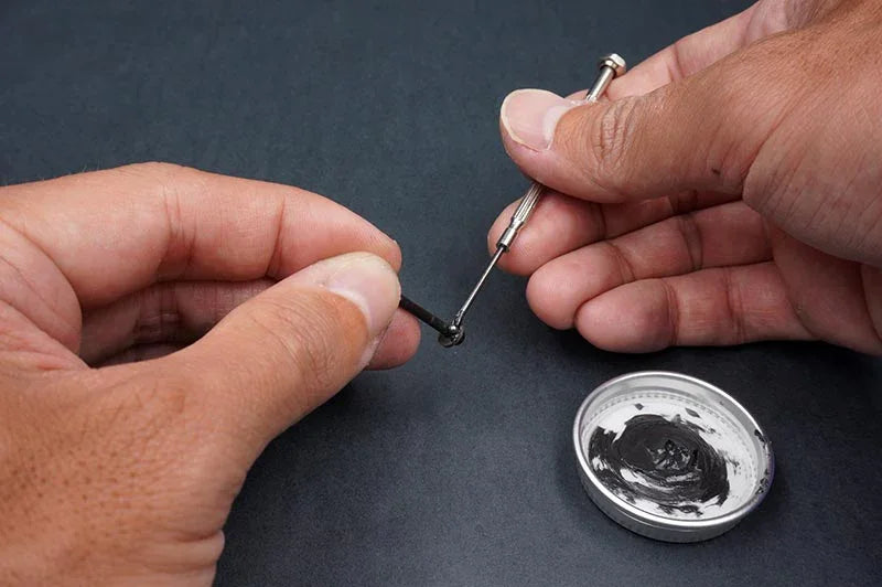 Koswork RC car accessory, applying black grease to metal part with small screwdriver