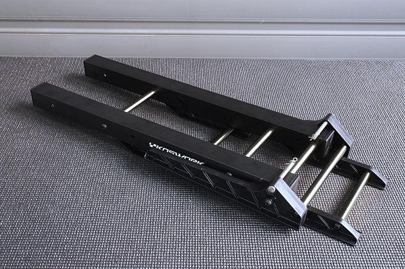 Black adjustable RC car stand with metal rods on a gray carpeted floor