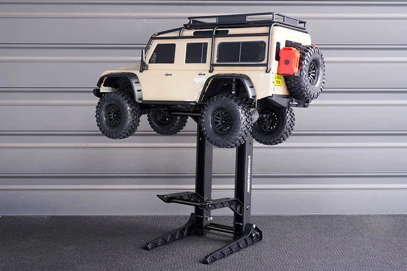 RC truck displayed on adjustable black RC car stand in a garage setting