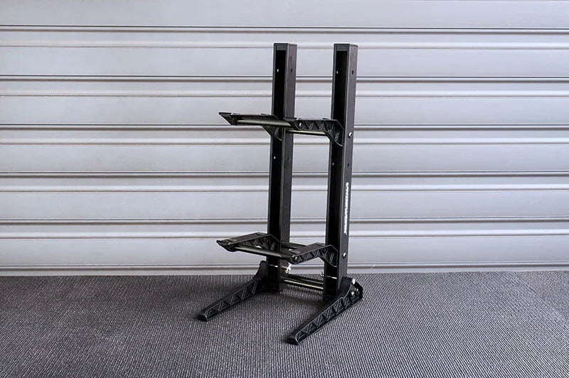 Black RC car stand with dual-tier slots on textured garage floor