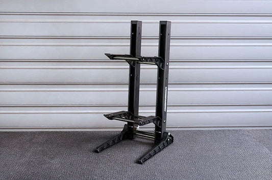 Black RC car stand with dual-tier slots on textured garage floor