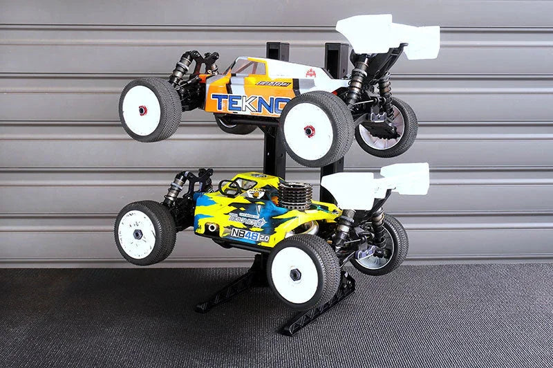 Double RC car stand holding two 1/8 scale racing buggy cars in a garage setting
