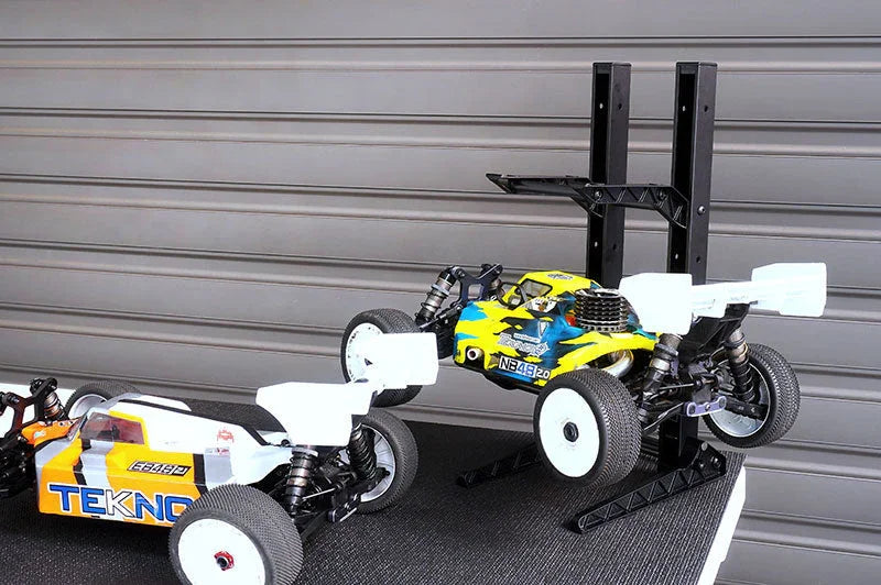 RC car storage stand holding two off-road racing buggies on a table