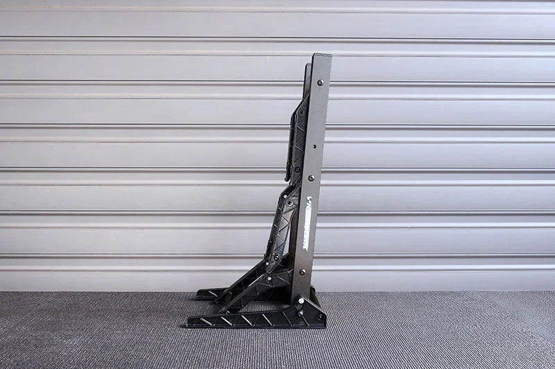 Black adjustable RC car pit stand on gray surface with horizontal panel background