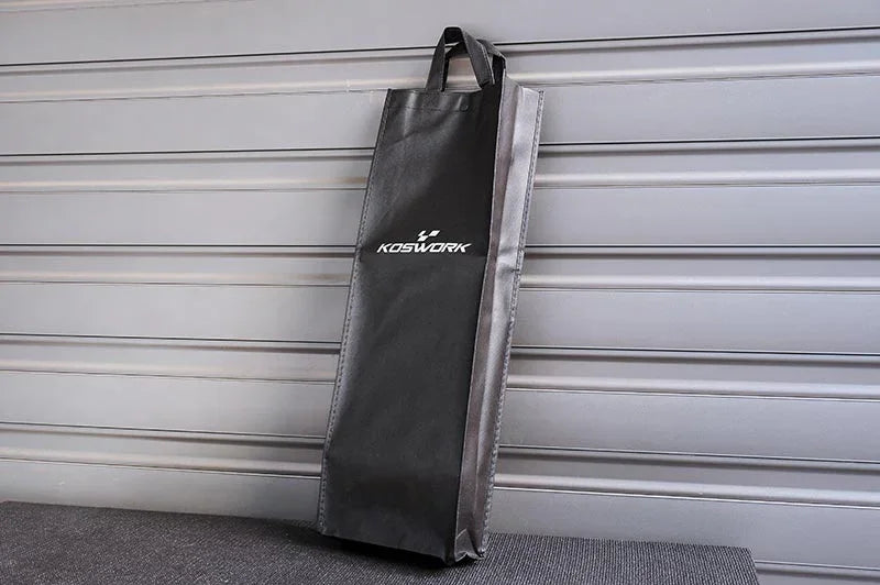 Black Koswork RC pit bag with handles leaning against a metal background