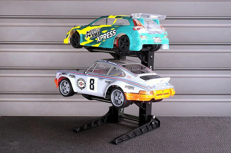 Dual RC car display stand holding two RC racing cars in a hobby workshop setting