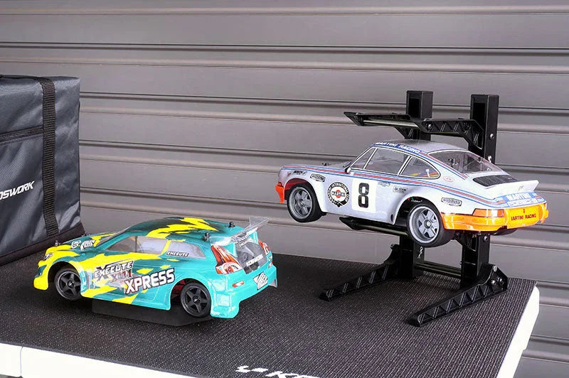 Two RC cars on a tool bench, one on a black adjustable RC car stand, ideal for maintenance.