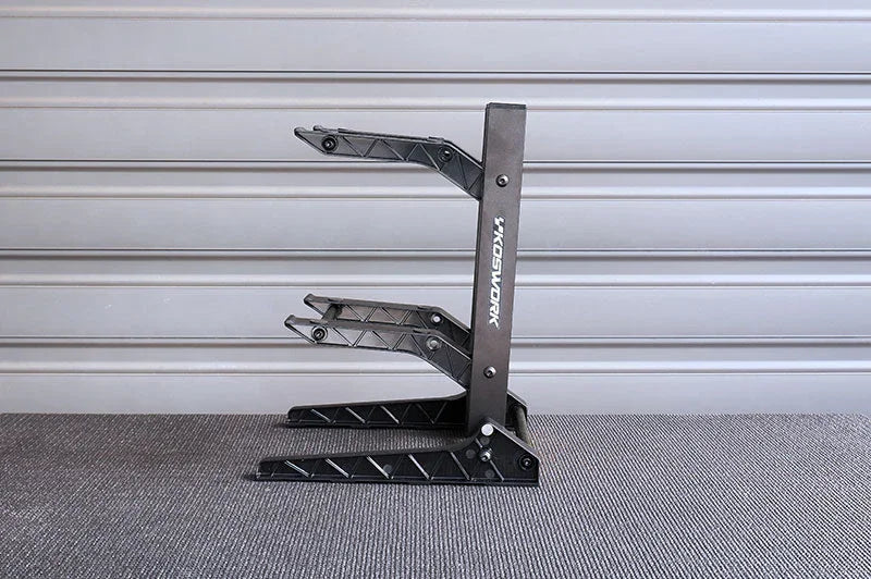 Black RC car multi-level pit stand with textured arms on indoor carpeted floor