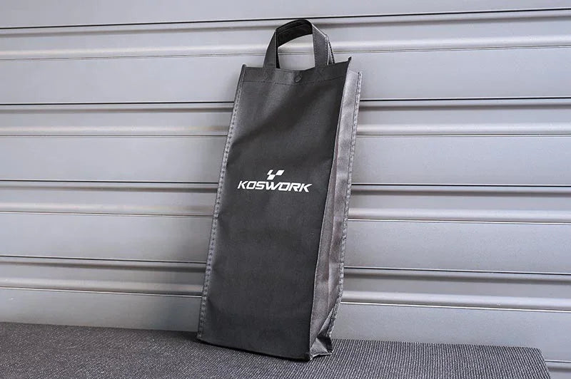 Black Koswork RC pit bag with handle, standing upright against a gray wall panel