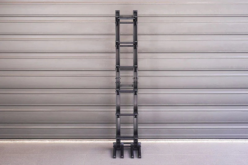 Black RC crawler ramp or obstacle track section standing upright against a gray wall