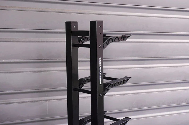 Black RC car display stand with three angled shelves against a metal wall